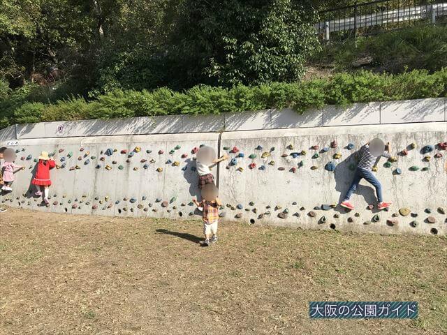 枚岡公園「みんなの広場」にあるクライミングウォールで遊ぶ複数の子供たち