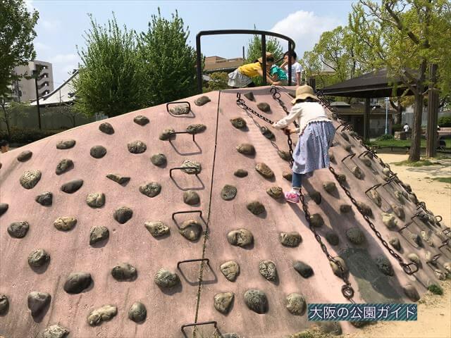 城北公園の遊具、石の滑り台を上る様子