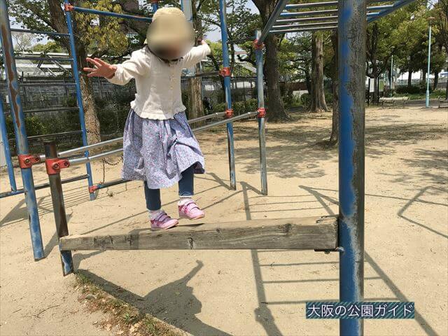 城北公園の遊具、平均台を歩く子ども