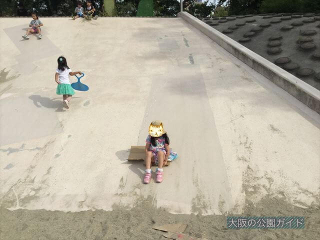 住之江公園の石の滑り台。段ボールに乗って滑る様子